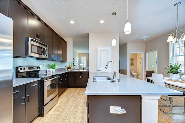 kitchen featuring dark brown cabinetry, a kitchen island with sink, sink, and stainless steel appliances