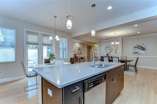 kitchen featuring dishwasher, sink, decorative light fixtures, a center island with sink, and light wood-type flooring