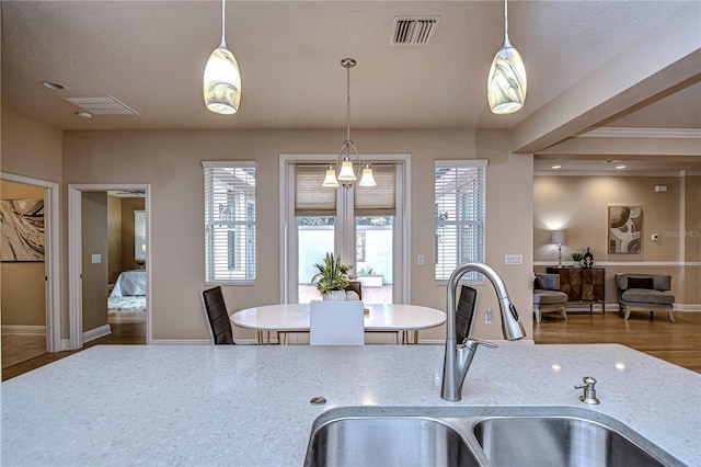 kitchen with a chandelier, hardwood / wood-style floors, hanging light fixtures, and sink