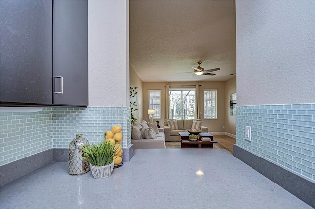 living room featuring ceiling fan and a textured ceiling