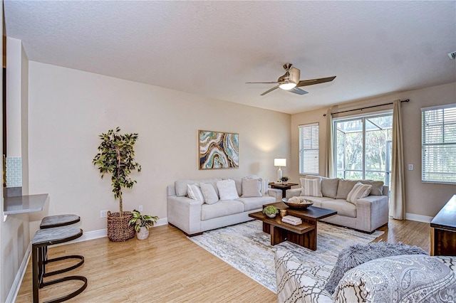 living room featuring a textured ceiling, light hardwood / wood-style flooring, and ceiling fan