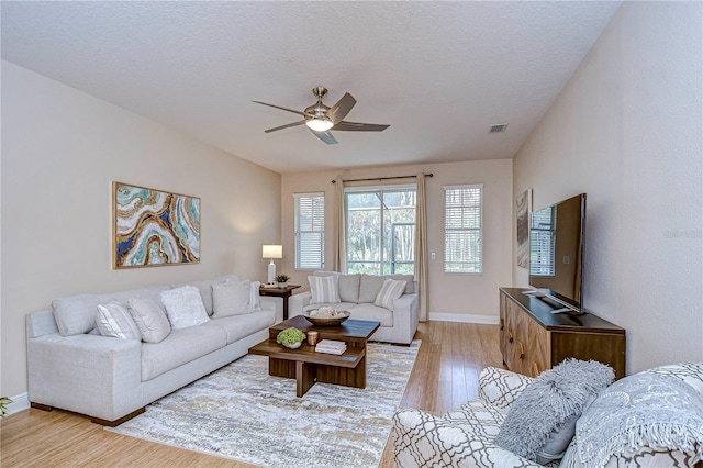 living room featuring ceiling fan, light hardwood / wood-style floors, and a textured ceiling