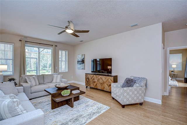 living room featuring a textured ceiling, light hardwood / wood-style floors, and ceiling fan