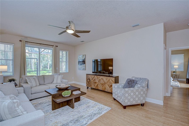 living room featuring a textured ceiling, light wood-type flooring, and ceiling fan