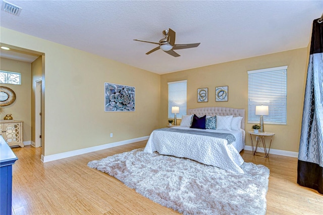 bedroom with ceiling fan, a textured ceiling, and light hardwood / wood-style flooring