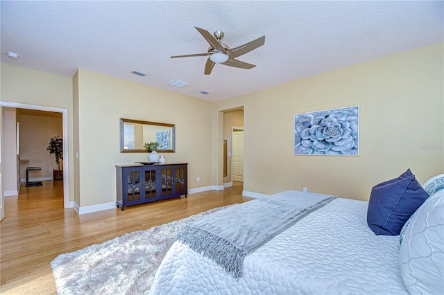 bedroom with ceiling fan, light hardwood / wood-style floors, and a textured ceiling