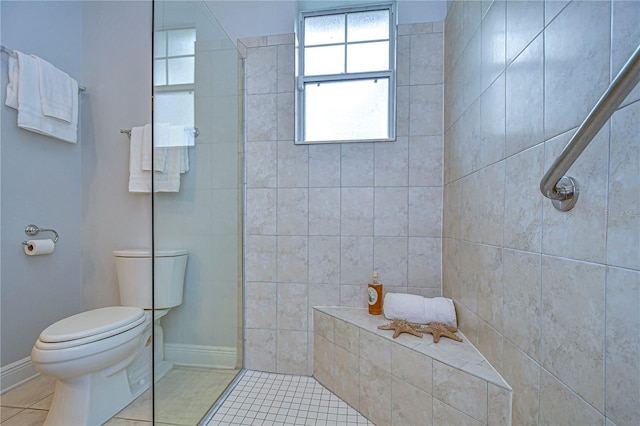 bathroom with tile patterned floors, toilet, and a tile shower