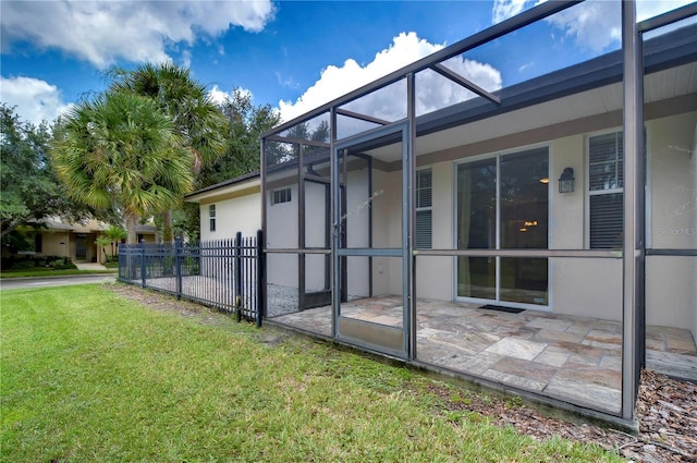 view of side of home with glass enclosure, a patio area, and a lawn