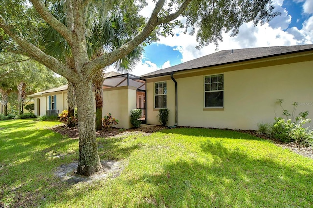 back of house featuring a lanai and a lawn