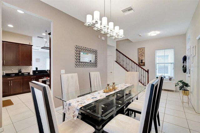 tiled dining room with a chandelier