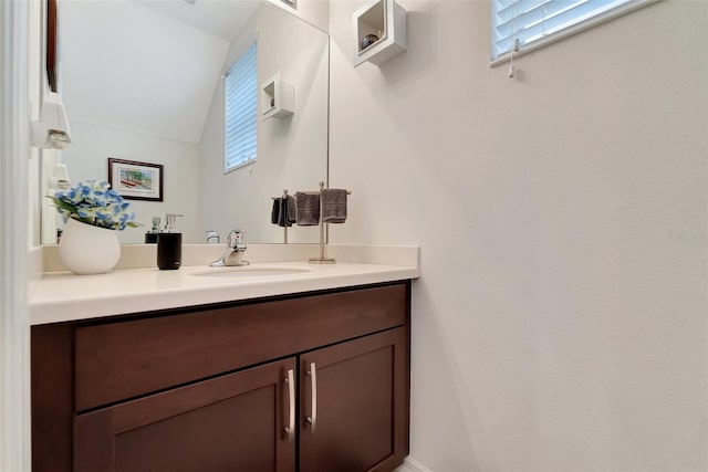 bathroom with vanity, lofted ceiling, and a healthy amount of sunlight