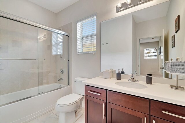 full bathroom featuring vanity, combined bath / shower with glass door, toilet, and tile patterned flooring