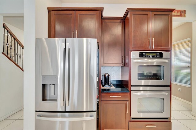 kitchen with baseboards, dark countertops, stainless steel appliances, and light tile patterned flooring