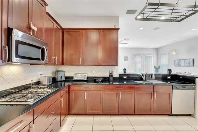 kitchen with backsplash, stainless steel appliances, visible vents, and a sink