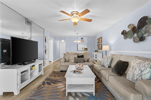 living room with ceiling fan with notable chandelier, a textured ceiling, and hardwood / wood-style flooring