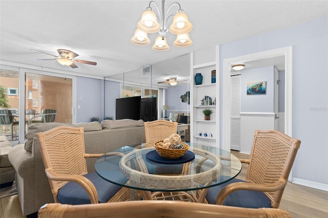 dining space featuring light hardwood / wood-style flooring, ceiling fan with notable chandelier, and a textured ceiling