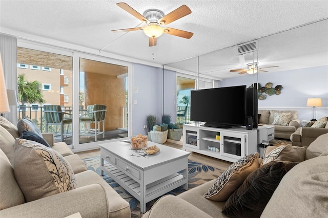 living room featuring ceiling fan, a textured ceiling, and expansive windows