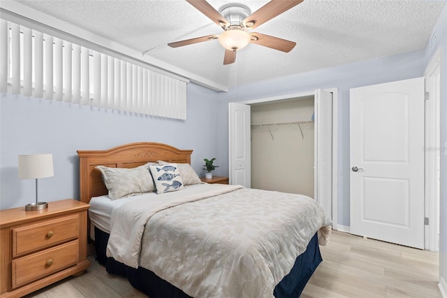 bedroom featuring ceiling fan, light wood-type flooring, a textured ceiling, and a closet