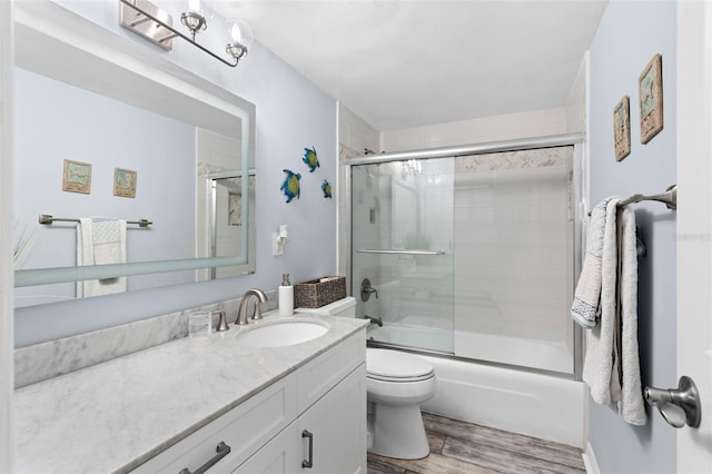 full bathroom with shower / bath combination with glass door, toilet, vanity, and hardwood / wood-style flooring