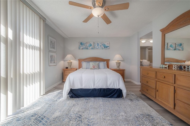 bedroom with a textured ceiling, light wood-type flooring, and ceiling fan