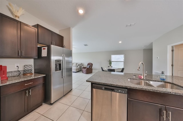 kitchen featuring light stone counters, appliances with stainless steel finishes, dark brown cabinetry, and light tile patterned floors