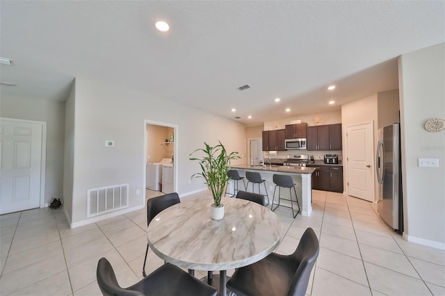 dining room featuring light tile patterned floors, sink, and washer and clothes dryer