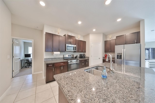 kitchen featuring dark brown cabinets, stainless steel appliances, light stone counters, light tile patterned floors, and sink