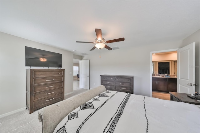 bedroom featuring light colored carpet, ceiling fan, and ensuite bath