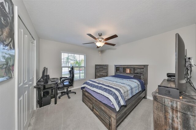 carpeted bedroom with ceiling fan, a textured ceiling, and a closet