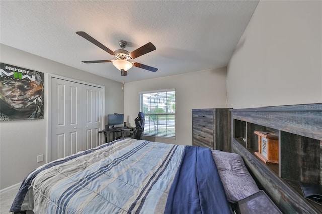 carpeted bedroom with ceiling fan, a textured ceiling, and a closet