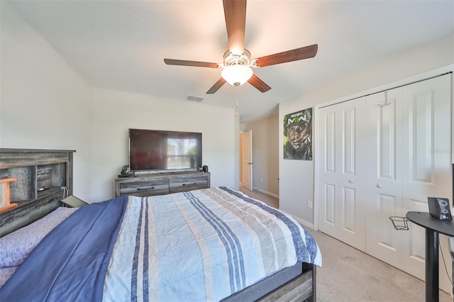 bedroom featuring ceiling fan, light colored carpet, a fireplace, and a closet