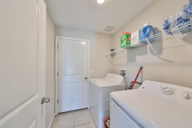 laundry area with washing machine and clothes dryer and light tile patterned floors