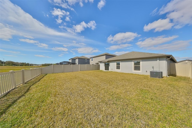 back of house with central AC and a lawn