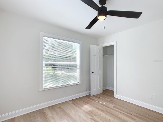 unfurnished bedroom featuring a closet, multiple windows, ceiling fan, and light hardwood / wood-style flooring