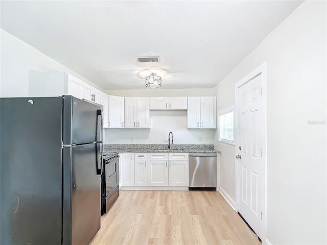 kitchen with light wood-type flooring, light stone counters, sink, black appliances, and white cabinetry