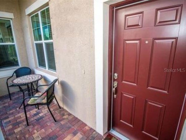 doorway to property featuring covered porch and stucco siding