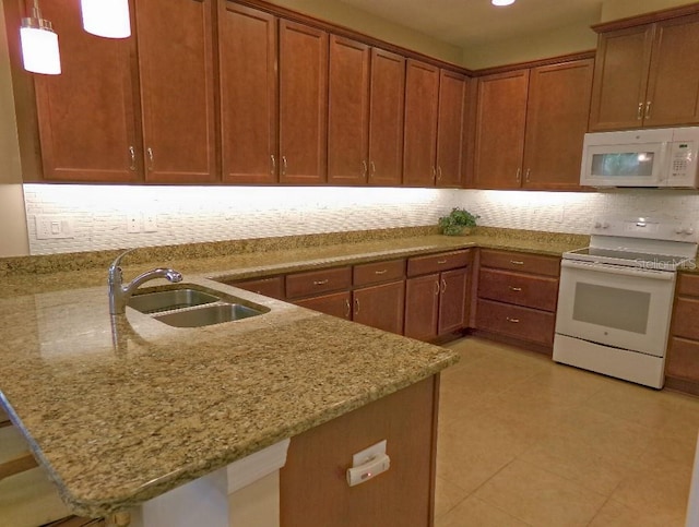 kitchen with backsplash, hanging light fixtures, light stone countertops, sink, and white appliances