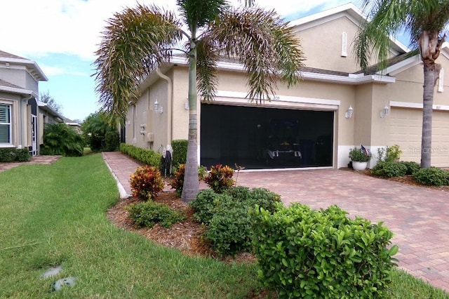 view of side of home featuring a garage, decorative driveway, and stucco siding