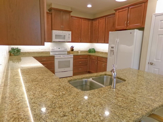 kitchen featuring sink, decorative backsplash, light stone countertops, white appliances, and kitchen peninsula