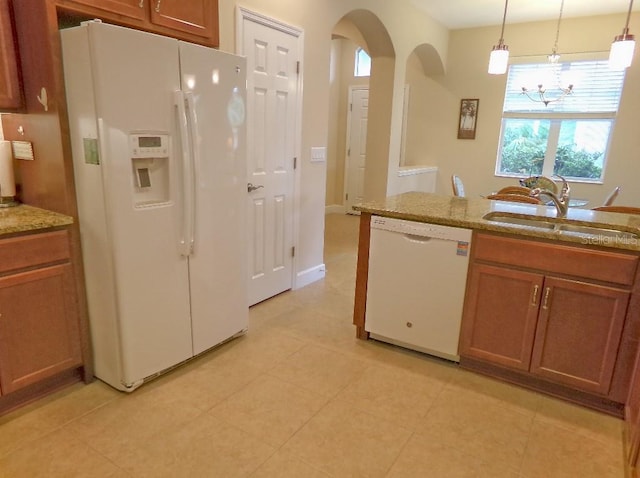 809 Chipper Dr, Sun City Center, FL 33573 - kitchen with white appliances, arched walkways, brown cabinetry, hanging light fixtures, and a sink