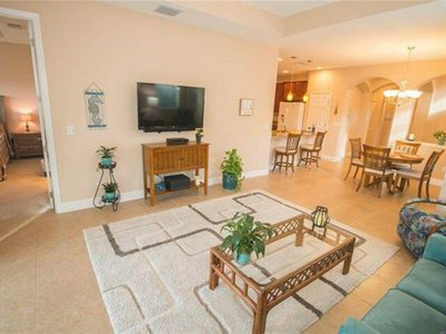 809 Chipper Dr, Sun City Center, FL 33573 - tiled living room with visible vents, a notable chandelier, and baseboards