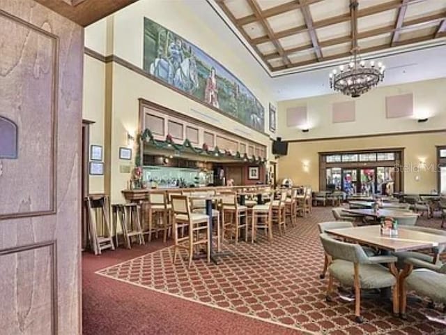 809 Chipper Dr, Sun City Center, FL 33573 - dining room with carpet floors, a high ceiling, an inviting chandelier, coffered ceiling, and beamed ceiling