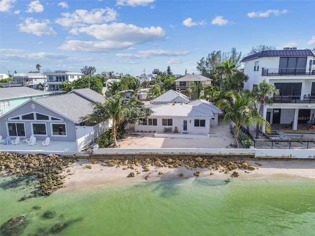 rear view of property featuring a patio, a view of the beach, a balcony, and a water view