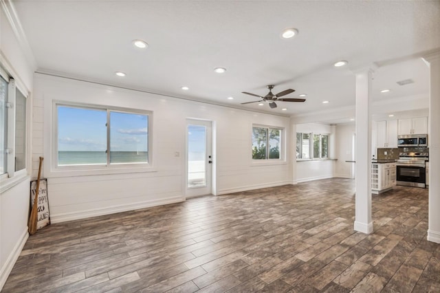 unfurnished living room with a wealth of natural light, ceiling fan, crown molding, and dark hardwood / wood-style floors