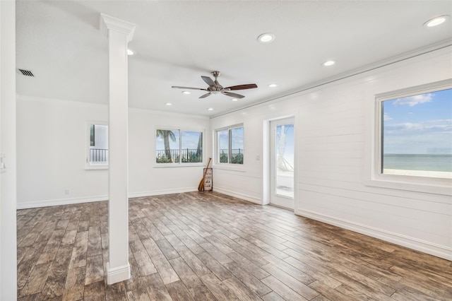 spare room with decorative columns, ceiling fan, ornamental molding, and hardwood / wood-style flooring