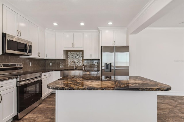 kitchen featuring stainless steel appliances, dark hardwood / wood-style floors, sink, a center island, and dark stone countertops