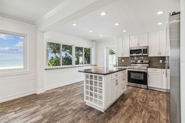 kitchen featuring backsplash, dark wood-type flooring, appliances with stainless steel finishes, dark stone countertops, and a center island