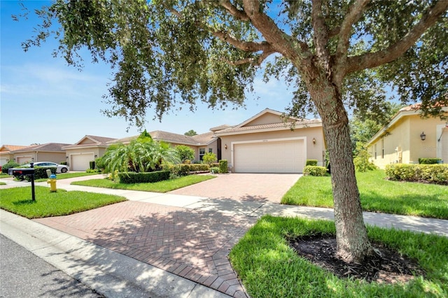 ranch-style house featuring a garage, a front lawn, decorative driveway, and stucco siding