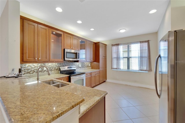 kitchen with glass insert cabinets, appliances with stainless steel finishes, brown cabinets, and light stone counters