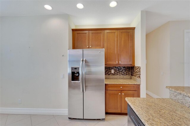 kitchen featuring brown cabinetry, light stone counters, stainless steel appliances, and decorative backsplash